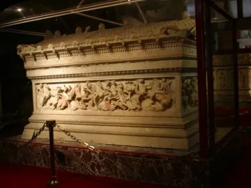 Alexander Sarcophagus with relief carvings, displayed in a glass case with a gold-chain barrier.