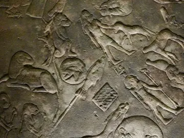 Close-up of the Dendera Zodiac showing weathered stone relief carvings with figures, animals, and celestial symbols.