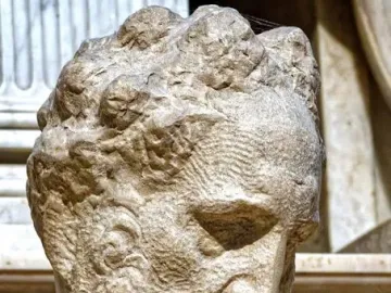 Close-up of Michelangelo’s Medici Chapel sculpture showing a bearded male figure with his head angled downward.