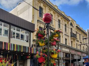 The Bucket Fountain sculpture in a light blue basin, decorated with colorful flower-filled buckets and a red sphere on top.