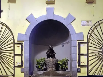 Jeanneke Pis bronze girl statue in a stone alcove with a small fountain below.