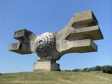 Monument to the Revolution of the People of Moslavina on a grassy hill, with a central circular concrete form and broad abstract wings.
