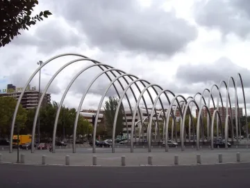 Puerta de la Ilustración, a large modern metal sculpture with curving parallel arches in an urban plaza.
