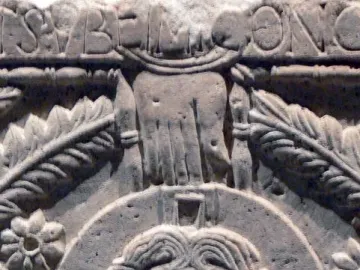 Close-up of the Rachis Altar relief showing a haloed face, an outstretched hand, and carved floral patterns.