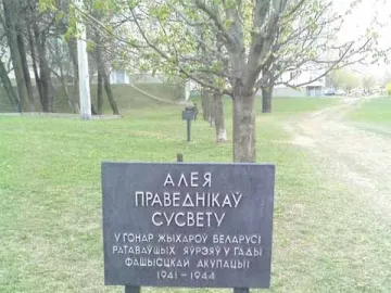 The Pit monument sign with Cyrillic text standing in a grassy area near trees.