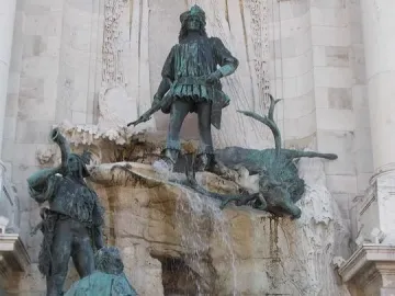 Fountain of King Matthias bronze sculpture showing a hunter with a fallen stag above figures and hunting dogs on rocky tiers.