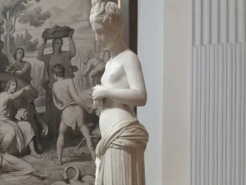 Pandora, a white marble neoclassical female statue with her head bowed and hands clasped in front of her torso.