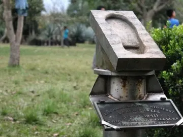 Weathered stone footprint monument on a rusty metal pedestal with a commemorative plaque.