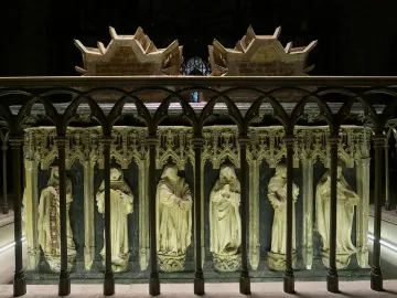 Tomb of Charles III and Eleanor with recumbent stone effigies, a lion at one figure\'s feet and two dogs at the other\'s, in a Gothic cathedral interior.