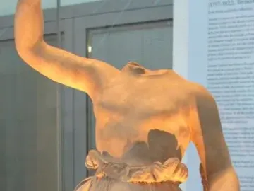 Hebe by Antonio Canova, a headless female statue with one arm raised and draped lower body in a museum display case.