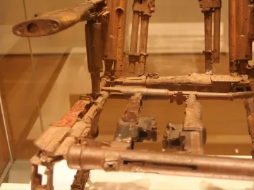 Close-up of Throne of Weapons made from rusted firearms and corroded metal parts behind glass.