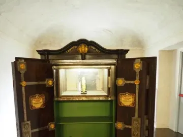 Venus of Chiozza displayed upright in a lit glass case inside an open wooden safe.