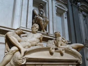 Michelangelo’s Dusk, showing two reclining marble figures beneath a seated figure in the Medici Chapel.