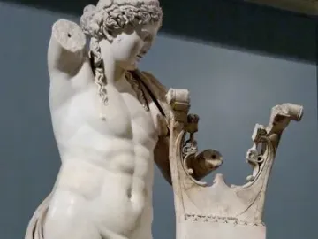 Apollo of Cyrene marble statue with a lyre-shaped support, missing its right arm and draped around the lower body.