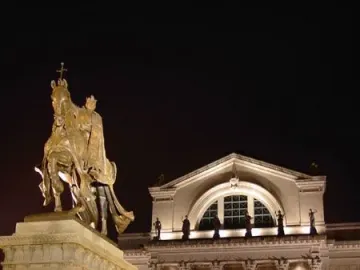 Apotheosis of St. Louis, an illuminated bronze equestrian statue on a tall pedestal in front of a lit classical museum building at night.