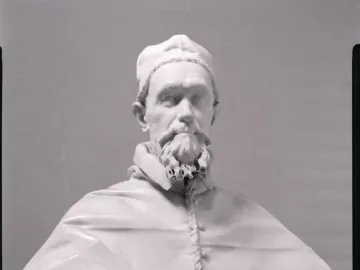 White marble bust of Pope Innocent X on a pedestal against a dark background.