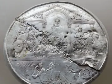 Disc of Theodosius showing a damaged silver relief with an enthroned figure, attendants, and a reclining female figure among wheat stalks.