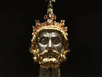 Bust of Charlemagne with a silver-toned face, golden beard, jeweled crown, and ornate gold reliquary chest.