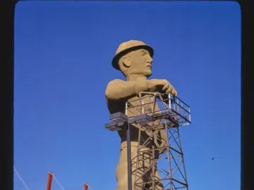 Golden Driller statue standing by a metal derrick structure in Tulsa, Oklahoma.