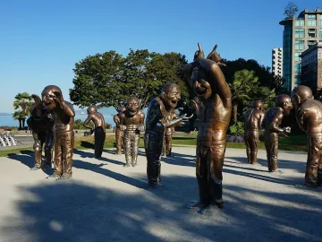 A-maze-ing Laughter sculptures of bald men with laughing expressions in a waterfront park.