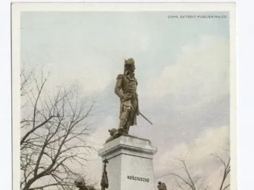 Tadeusz Kościuszko statue on a tall white pedestal with bronze figures and an eagle at the base.