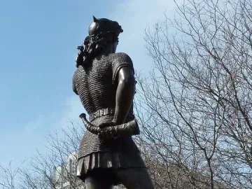 Rear view of the Leif Ericson statue in bronze, showing a figure in chainmail and a horned helmet holding a curved horn.