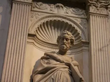 Saint Peter statue of a bearded man holding a scroll or book in a decorative niche.