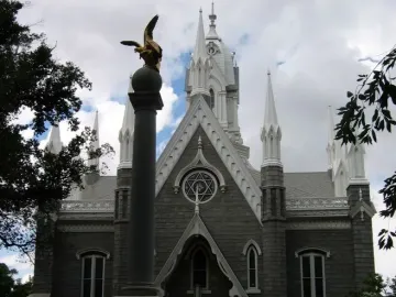 Seagull Monument with a golden bird sculpture in front of the Assembly Hall\'s grey stone facade and white spires.