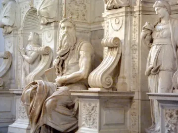 Marble sculpture of Moses seated with tablets, shown with a bearded face and horn-like protrusions.