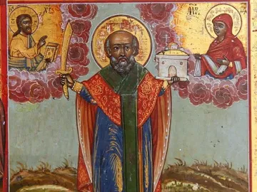 Saint Nicholas of Mozhaysk standing in ornate robes, holding a sword and a small church model.