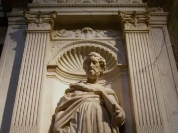 Saint Peter marble statue in an ornate niche, holding a book and wearing flowing robes.