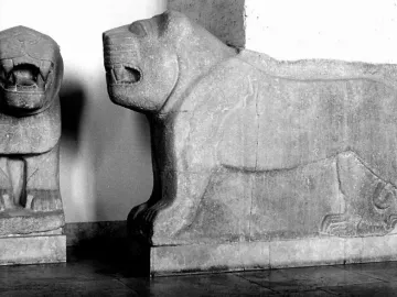 Two ancient stone lion sculptures, one shown frontally with an open mouth and the other in profile.