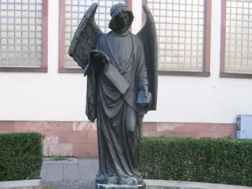 Frankfurter Engel sculpture showing a winged figure in flowing robes holding a scroll and a small book or box.