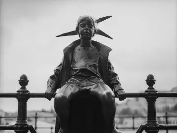 The Little Princess statue sits on a decorative railing, shown in black and white with a distant landscape behind it.