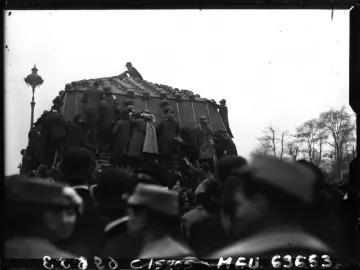 The Marly Horses covered with helmets, with people climbing on the monument and a crowd watching below.