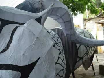 Alebrije sculpture with crinkled white surface, black stripes, and a curved segmented horn