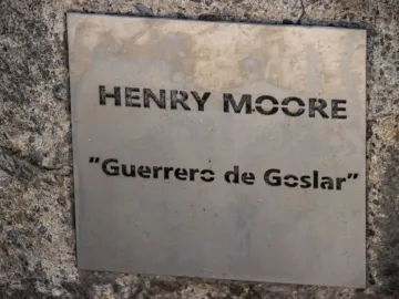 Metal plaque on a rough stone wall reading Henry Moore and Guerreros de Goslar.