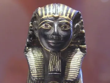 Thutmose III sphinx figurine in profile with gold inlays on a dark background