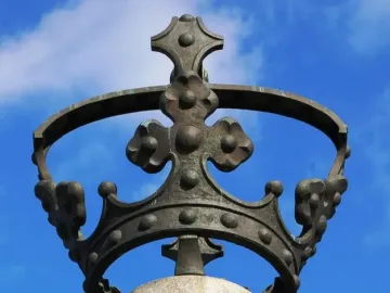 Electio Viritim Monument bronze crown on a stone pillar against a blue sky.