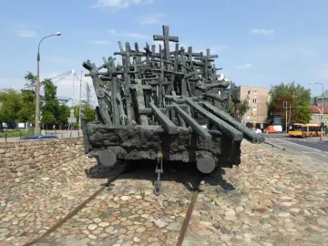 Monument to the Fallen and Murdered in the East, a dark sculpture shaped like a railway flatcar covered with crosses and beam-like forms