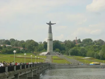 The Mother Patroness statue stands on a tall pedestal with outstretched arms, reached by steps and fountains.