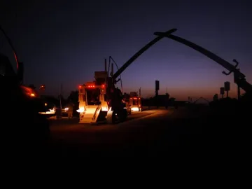 Victory Arch silhouetted against a twilight sky with vehicles and red taillights in the foreground.