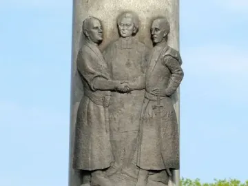 Electio Viritim Monument in Warsaw with a bronze plaque below a relief of three historical figures.