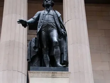Statue of George Washington on a stone pedestal with engraved text on the base.