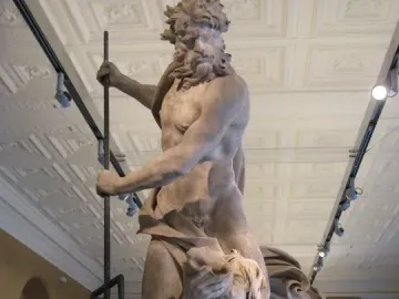 Neptune and Triton marble sculpture showing Neptune holding a trident over a kneeling Triton in a museum hall.