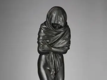 Winter, a dark bronze figure in a heavy draped robe with arms crossed over the chest.