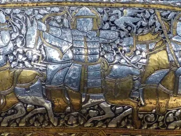 Battle scene panel from the Baptistery of Saint Louis showing armored horsemen, bows, spears, and scrolling foliage.