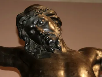 Upper body of Bernini\'s Corpus bronze sculpture showing Christ with a crown of thorns, head tilted and eyes closed.