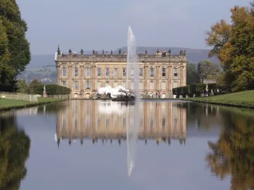 Emperor Fountain rising from a reflecting pool in front of a grand historic mansion