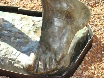 Close-up of the bronze foot detail of Jean de Fiennes, with textured patina and a rough base.
